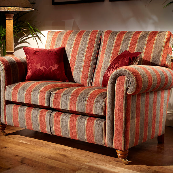 Striped sofa with red cushions in a room with plants and a lamp.