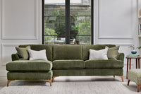 Green sectional sofa in a living room with large windows.