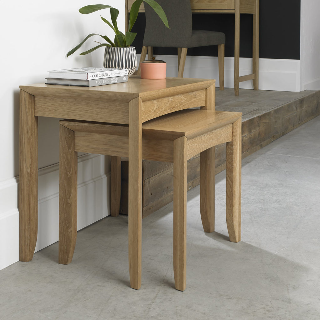 Wooden nesting tables with a plant and books on top in a room setting.