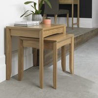 Wooden nesting tables with a plant and books on top in a room setting.