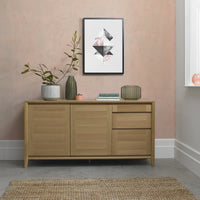 Wooden sideboard with decorative items against a pink wall