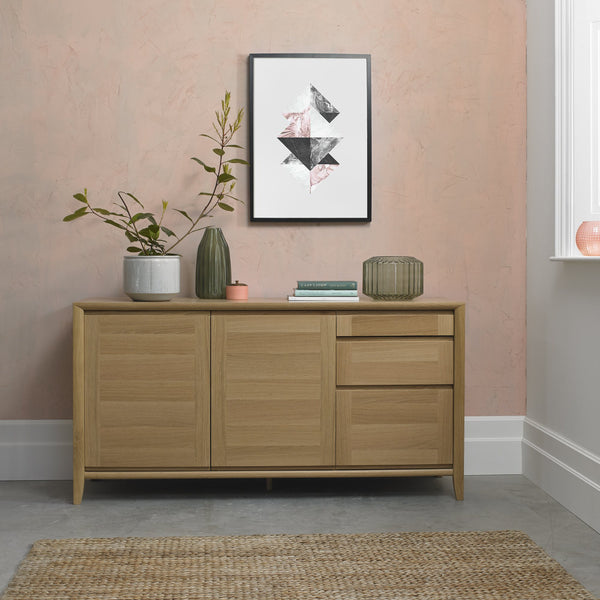 Wooden sideboard with decorative items against a pink wall