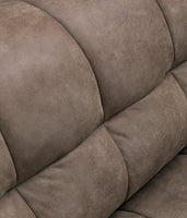 Close-up of a tufted upholstered armchair in a warm taupe-brown leather, showing the padded channel tufting and soft texture.