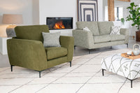 Living room with green armchair and grey sofa in front of a fireplace.