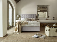 Modern bedroom with a grey upholstered bed, wooden floor, and large mirror.