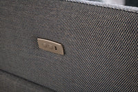 Close-up of a textured grey fabric surface with a metallic lock emblem.