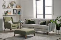 Living room with grey sofa, green armchair, and ottoman in a well-lit room.