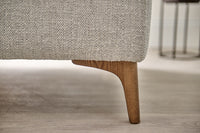 Close-up of a textured sofa with wooden legs on a light wood floor.