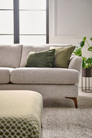 Grey sofa with green and patterned cushions in a living room setting.