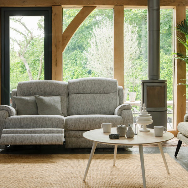 Living room with grey sofa, round coffee table, and large windows.
