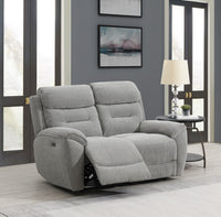 Grey recliner sofa in a living room setting with a lamp and window.