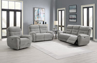 Grey reclining sofa set in a living room with large windows and neutral decor.