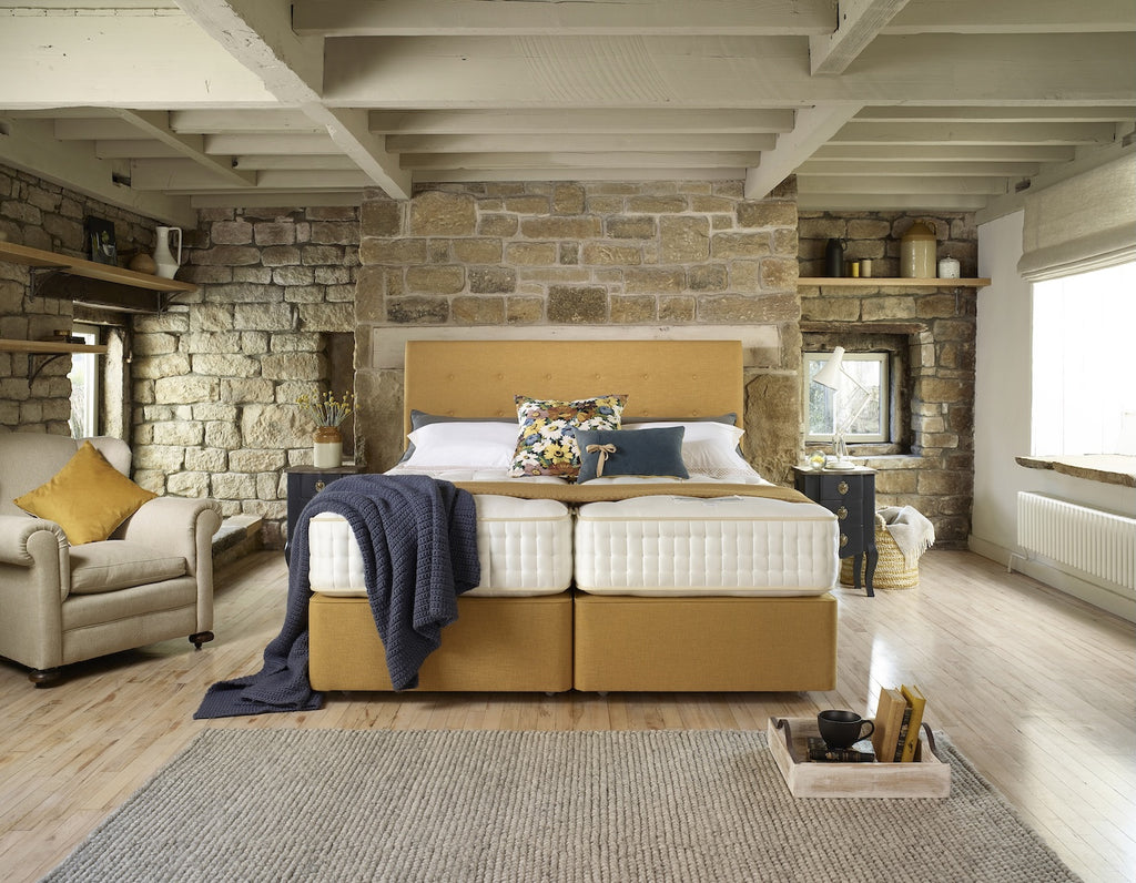 Modern bedroom with stone wall, wooden bed, and decorative pillows.