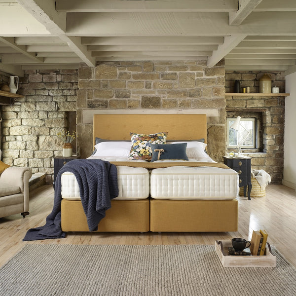 Modern bedroom with stone wall, wooden bed, and decorative pillows.