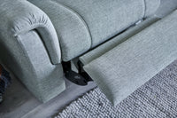 Grey recliner sofa with one armrest and seat extended on a carpeted floor.