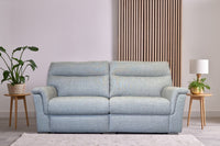 Light blue sofa in a room with a plant and side tables.