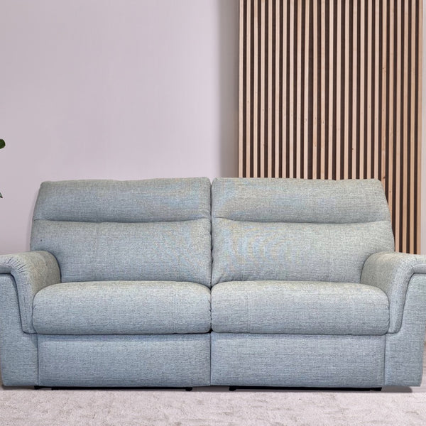 Light blue sofa in a room with a plant and side tables.