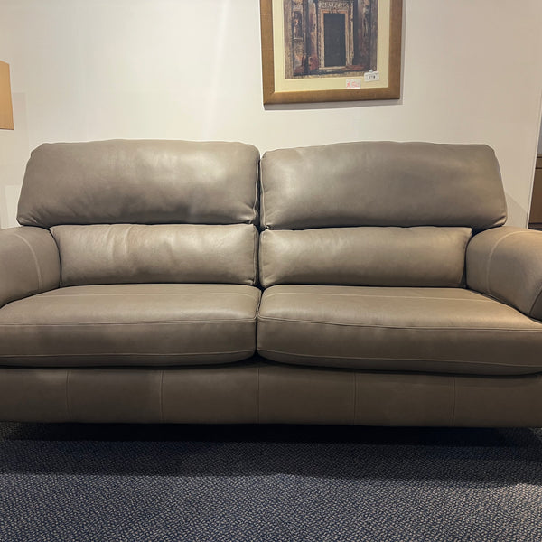 Grey leather sofa in a room with a lamp and framed picture on the wall.