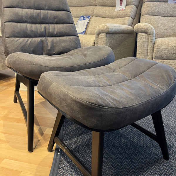 Grey recliner chair with stool in a showroom setting