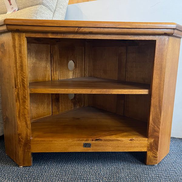Wooden corner TV stand in a room with a sofa.