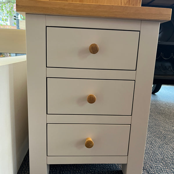 Wooden drawer unit with three drawers and wooden knobs on a carpeted floor.