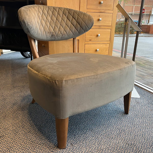 Gray upholstered stool with wooden legs on a carpeted floor.