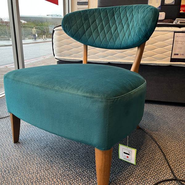 Teal stool with wooden legs in a showroom setting