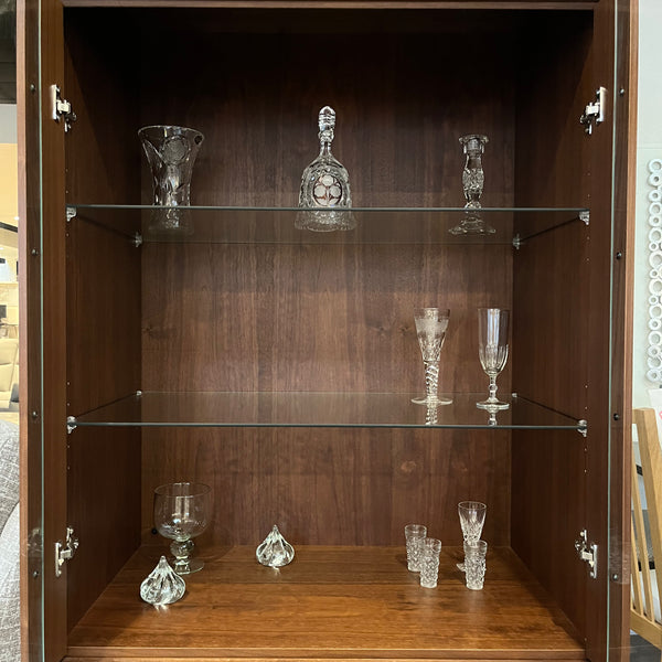 Wooden display cabinet with glass shelves containing decorative items.