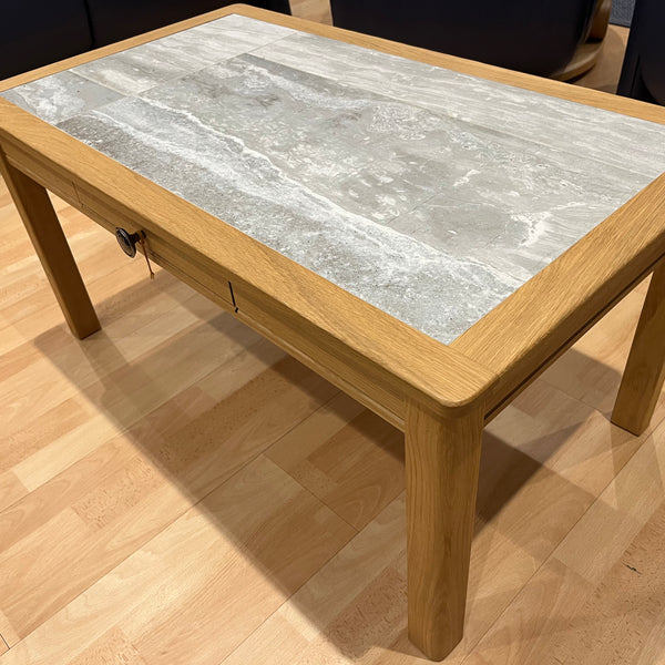 Wooden coffee table with a marble-like top on a wooden floor.