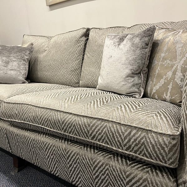 Grey patterned sofa with decorative pillows in a room setting.