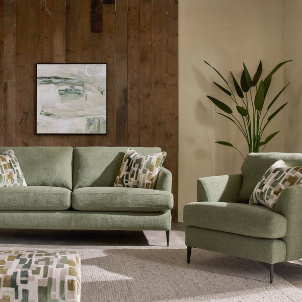 Green sofa and armchair in a living room with a wooden wall and plant.