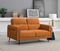 Orange sofa in a room with a grey wall, books, and decorative items.