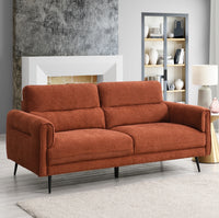 Rust sofa in a living room setting with a fireplace and bookshelf.