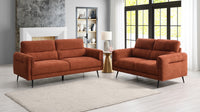 Two orange sofas in a living room setting with a rug and lamp.