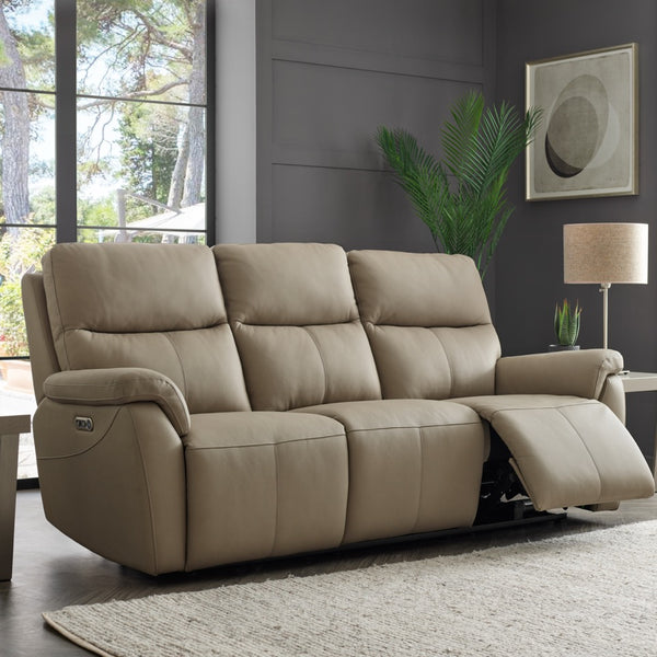 Beige reclining sofa in a living room setting with large windows and a plant.