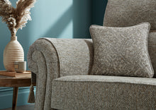 Load image into Gallery viewer, Grey textured sofa with a decorative pillow against a blue wall
