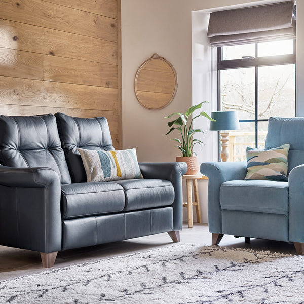 Blue sofa and armchair in a living room with wooden walls and large windows.