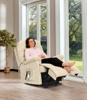 Woman relaxing in a beige recliner chair in a bright room with large windows.