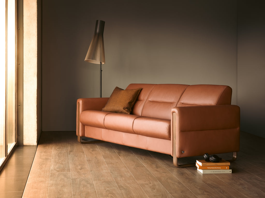 Brown leather sofa in a room with wooden flooring and a tall floor lamp.