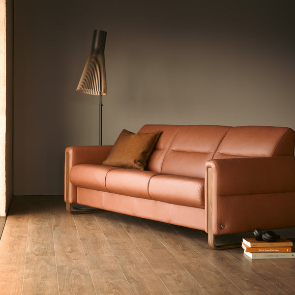 Brown leather sofa in a room with wooden flooring and a tall floor lamp.