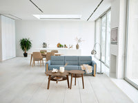 Modern living room with a blue sofa, wooden coffee table, and large windows.