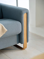 Grey sofa with wooden legs on a light wooden floor