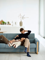 Two people sitting on a blue couch in a modern living room.