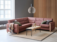 Pink sectional sofa in a living room with a coffee table and decorative items.