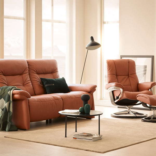 Living room with brown leather sofa, chair, and stressless in a bright room.