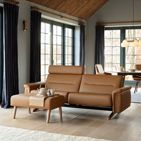 Tan leather sofa in a modern living room with large windows.