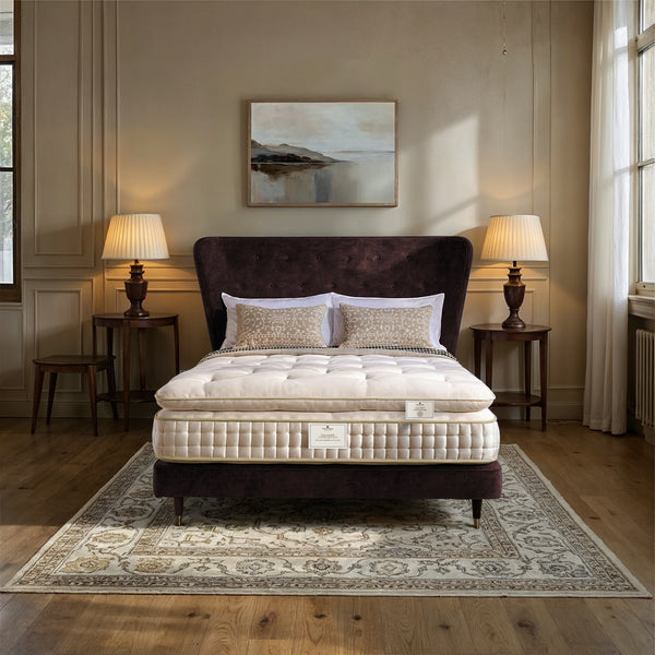 Mattress on a bed in a bedroom with lamps and artwork on the wall.
