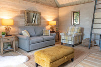 Living room with grey sofa, yellow ottoman, and plaid armchair.