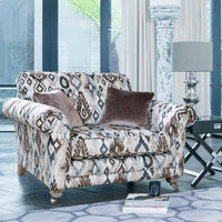 Patterned armchair with brown cushions in a room with large windows and a lamp.