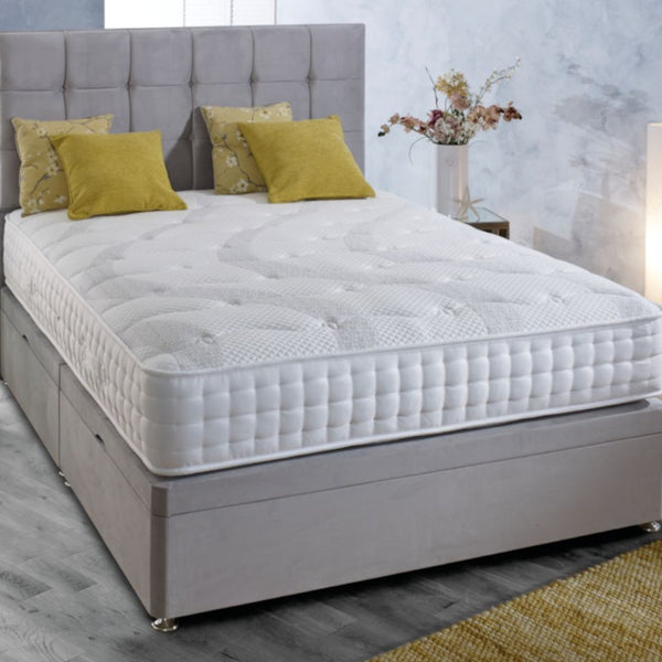 Bed with white mattress and grey headboard in a bedroom setting